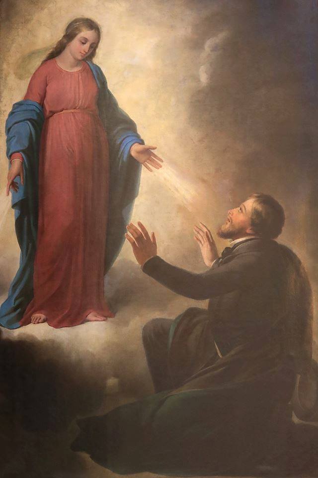 La Virgen, de pie sobre una nube, con rayos de luz que salen de sus manos, se aparece a un hombre arrodillado con los brazos abiertos